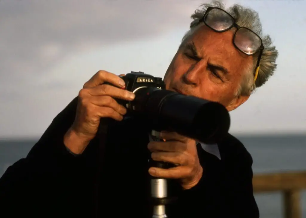 retrato em cor do fotógrafo Ernst Haas e sua câmera leica para ilustrar sua coleção de frases sobre fotografia