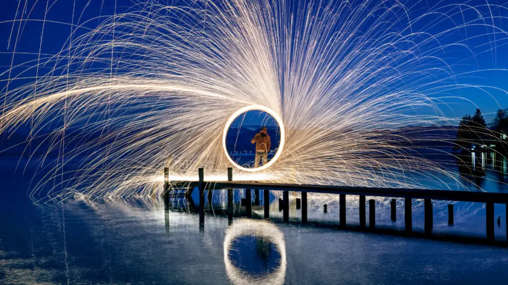 homem em ponte em um lago fazendo efeito steel wool usando técnica de diafragma na fotografia