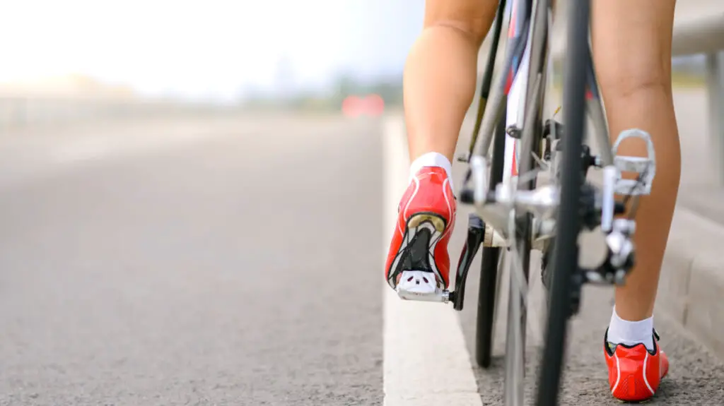 detalhe de pernas de mulher em uma bicicleta e fundo desfocado